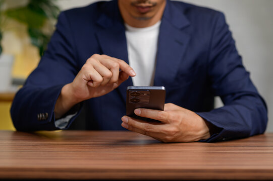 Professional Man Using Smartphone While Sitting at Wooden Table