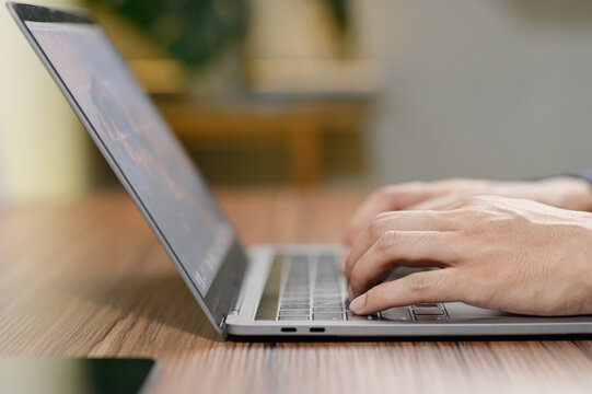 Hands Typing on Laptop Keyboard in Cozy Workspace Setting
