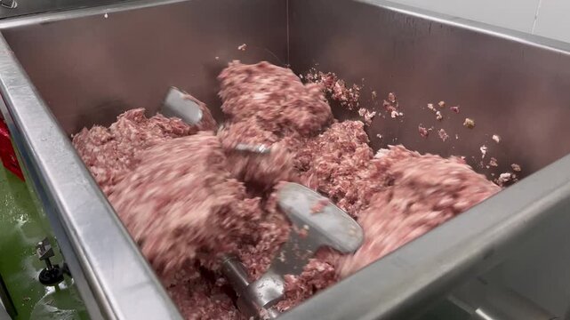 Raw meat filling being mixed in an industrial food mixer during food manufacturing operations. Ingredient blending process used to ensure product consistency, texture, and quality before further produ