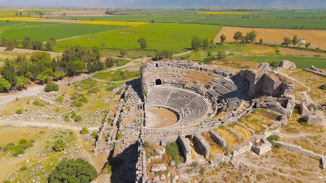 Balat, Turkey. The Roman Theatre of Miletus, a vast stone amphitheater with tiered seating rising from a sunlit archaeological site, aerial view over patchwork farmland. Aerial View, MasterShots, Spi