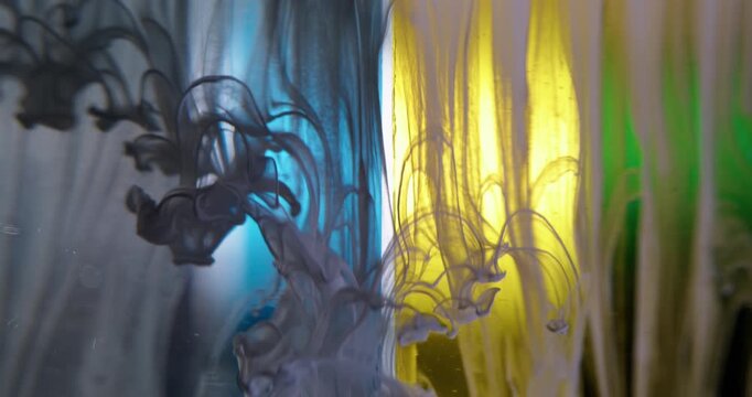 Paint background. Liquid splash. Defocused blue yellow green colorful water acrylic swirling drip spilling on creative abstraction.