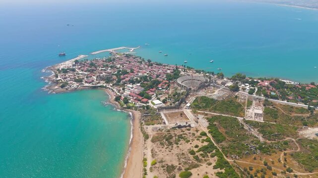 Side, Manavgat, Turkey. Ancient peninsula with Roman amphitheater and Agora square, panoramic aerial view over turquoise Mediterranean waters under clear summer sky. Aerial View