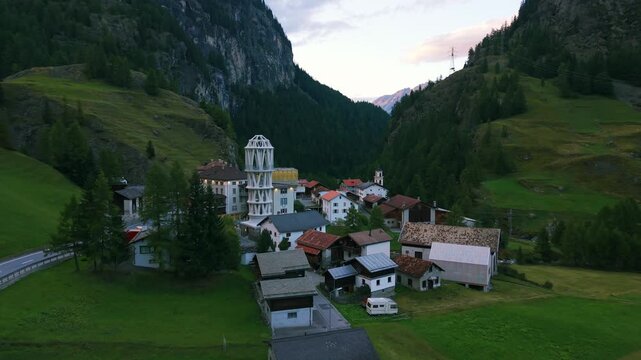 Drone view of Tor Alva, world's tallest 3D printed tower, futuristic landmark in traditional alpine village of Mulegns, Switzerland. Aerial backward