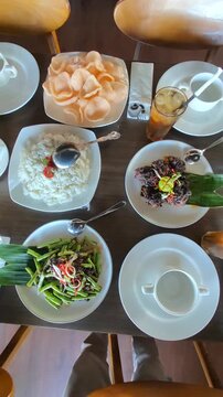 Overhead moving camera shot of an Asian dining table featuring multiple traditional dishes, iced drinks, soup, rice, and crispy meat presentation. Cinematic restaurant atmosphere with aesthetic food a