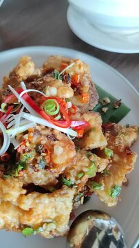 Smooth moving camera shot featuring several delicious Asian dishes served on a dining table, including stir-fried vegetables, crispy seafood, rice, and soup. Warm restaurant atmosphere with cinematic 