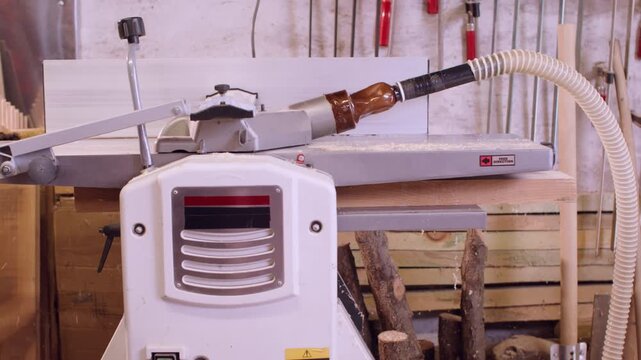 Carpentry process production. Joiner service. Man push plank in thickness machine preparing material for furniture making in garage interior.