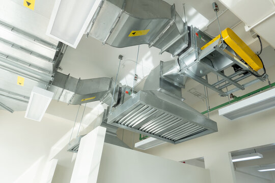 Industrial Ventilation System: A complex network of metal ducts and machinery forms an industrial ventilation system, showcasing a sophisticated mechanical installation within a building's ceiling.