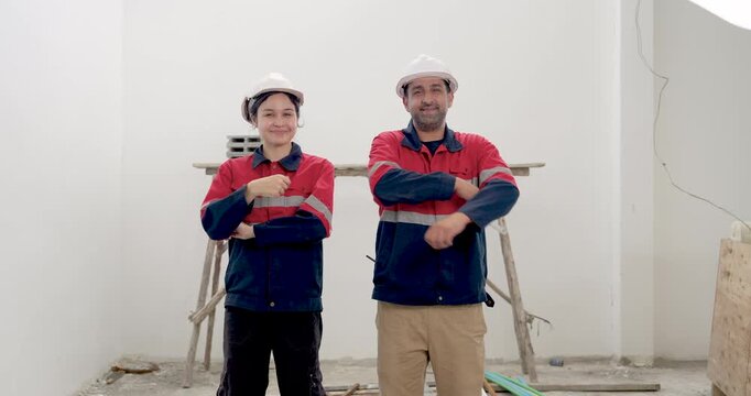 Asian female engineer and male supervisor stand in unfinished interior, discussing site work direction with folded arms, construction safety compliance, project progress, quality inspection indoors