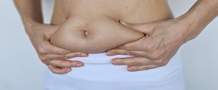 Fat woman hand holding fat belly on white background. Obesity cellulite problem