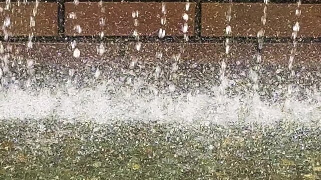 水しぶきや水滴のある流れる噴水　レンガの壁を噴出される水がはじける風景