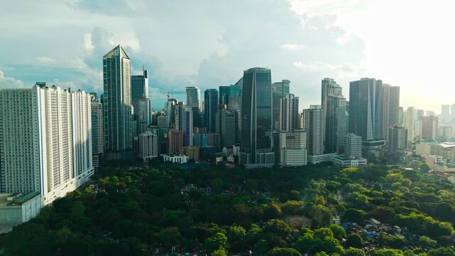Drone reveals Makati business towers beyond Manila South Cemetery at dusk