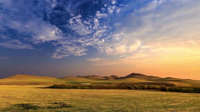 Golden sunset over rolling hills and vast prairie, dramatic sky with blue and orange clouds, peaceful rural landscape at dusk, wide open meadow scenery