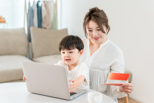 A single mother is looking at her computer and bankbook while holding her child.