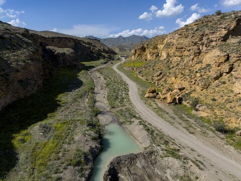 A path leads through a rocky valley with a narrow river flowing through the landscape, aerial view, on the way to Angel's Canyon, Dashtakar, Ararat Province, Armenia