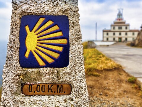 Kilometre zero with scallop shell, last kilometre stone of the Camino a Fisterra, in front of lighthouse, endpoint of the Way of St. James at Cape Finisterre, A Coru&ntilde;a province, Galicia, Spain
