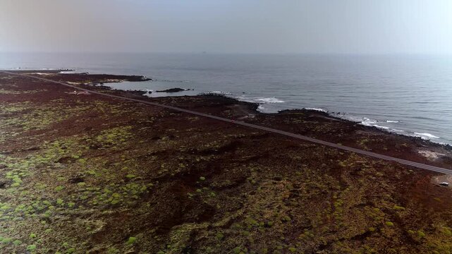Aerial pan of volcanic landscape and coastal road, Caleton Blanco, Lanzarote