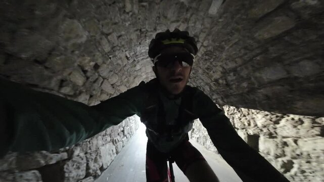 First-person cycling footage entering a mountain tunnel during an early morning ride. Natural light gradually fades as the cyclist moves deeper into the tunnel.