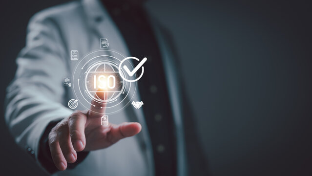 Businessman touches glowing virtual interface displaying international organization standardization certification symbols demonstrate quality management system compliance regulatory adherence.