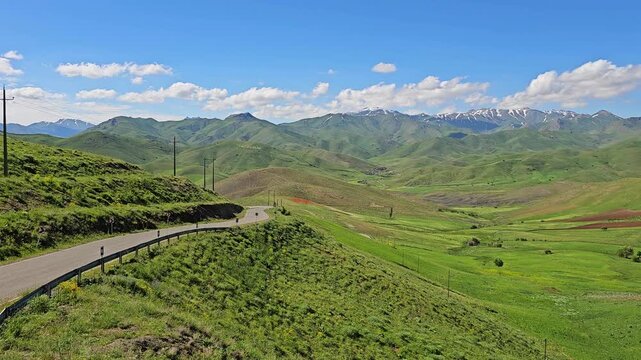 Rolling green hills with a winding road under bright blue sky and soft white clouds, showcasing peaceful spring countryside scenery.
📍 Marivan, Kurdistan, Iran 