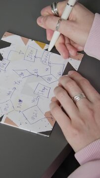Vertical close-up of hands of unrecognizable female software architect drawing block scheme for project on paper, developing roadmap and planning implementation workflow