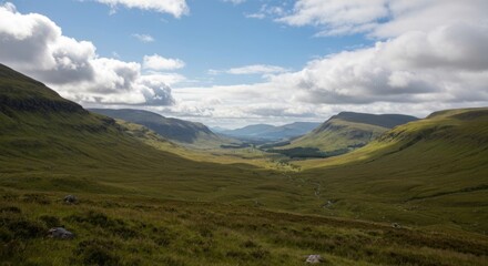 Fototapeta premium Vast green valley stretching between rolling hills under a cloudy sky