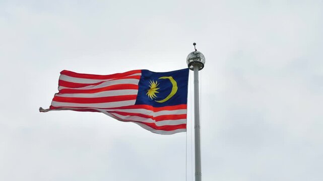 Malaysian National Flag Jalur Gemilang Waving on Flagpole Against cloudy Sky