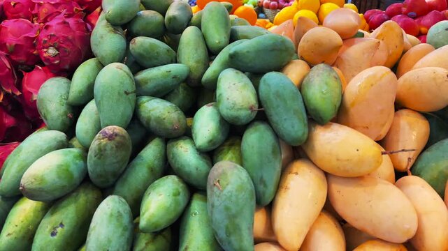 Colorful Tropical Fruit Display with Green Mangoes and Dragon Fruit at Market