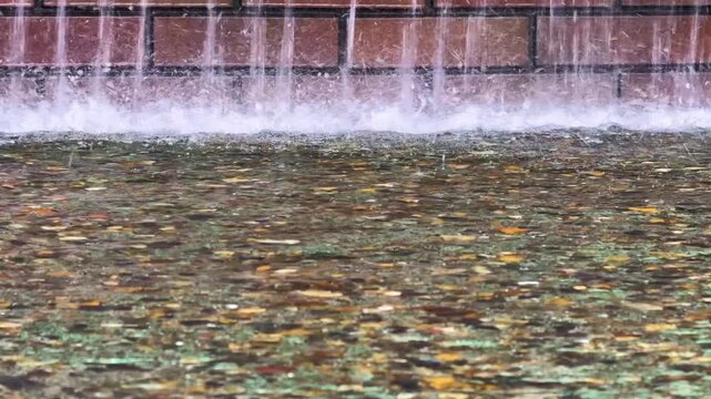 水しぶきや水滴のある流れる噴水　レンガの壁を噴出される水がはじける風景