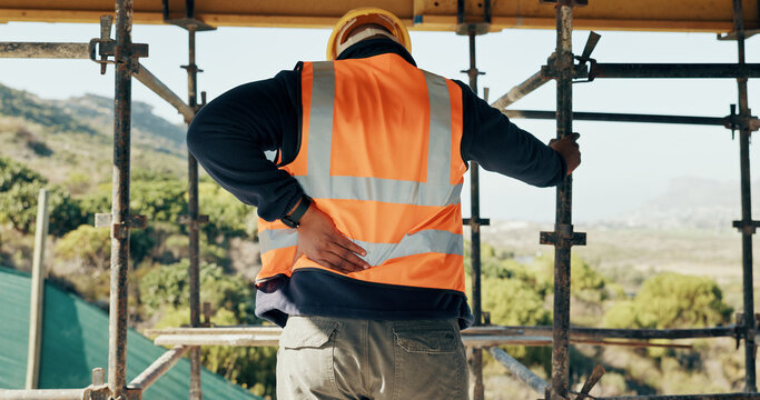 Construction, injury and man with back pain for accident, stress and overworked at building site. Architecture, engineering and person with pressure for fibromyalgia, muscle sprain and hurt outdoor
