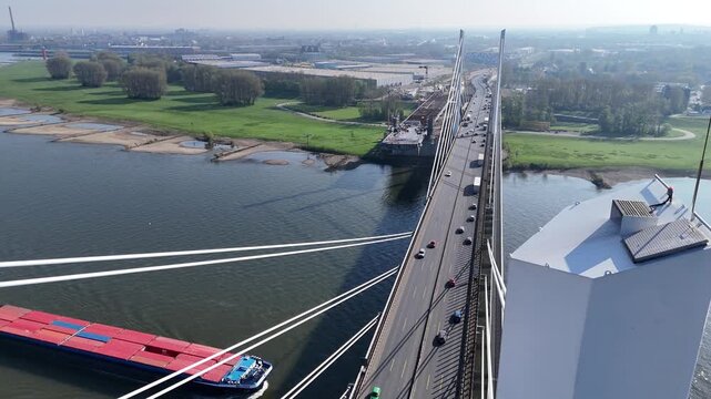 Close aerial detail of a bridge pylon, showing access hatch, lamp, lightning rod, and traffic far below.
