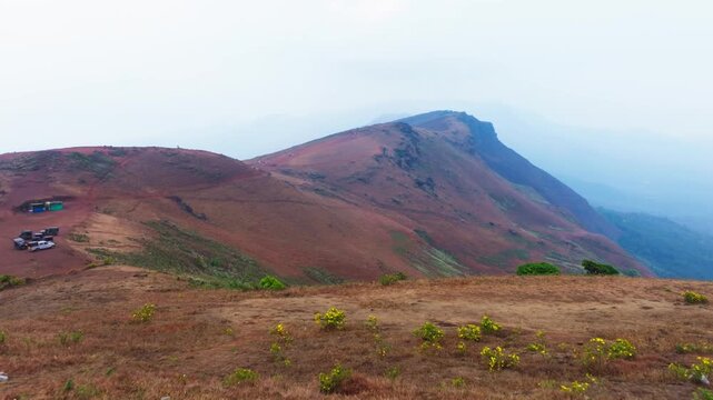 shooting sports venue with parked vehicles, haze, sky and mountain ridge at Baba Budangiri Hill Peak, Dattatreya Peeta, Chikkamagaluru, Karnataka, india. day time, push back shot, drone shot, 4k.