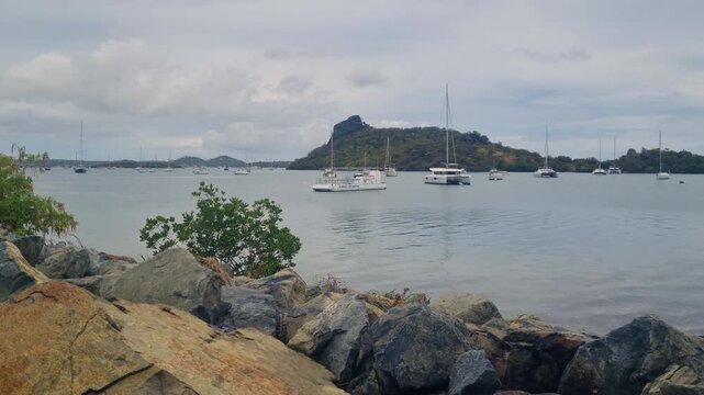 View over Simpson Bay Lagoon on Sint Maarten on a calm overcast day, with sailing boats and catamarans anchored in the tranquil turquoise water, surrounded by the peaceful tropical island landscape