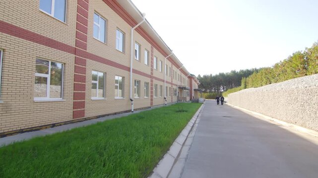 Multi story institutional facility stands beside paved driveway. Sunny weather highlights peaceful suburban atmosphere of university campus