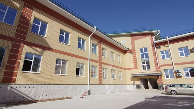 Contemporary brick educational facility features clean newly paved driveway. Deep blue sky creates pleasant contrast with architecture