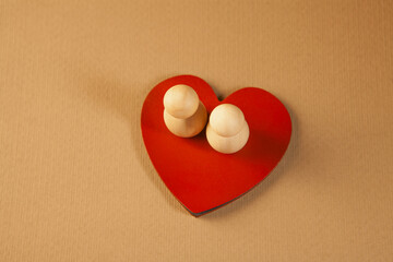 Fototapeta premium Two wooden figures in the form of a heart on a red background