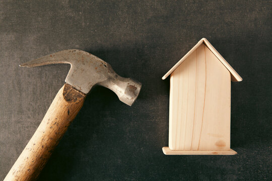 Hammer and wooden house on background. Concept of buying a house.