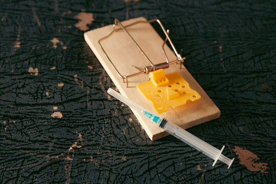 Mousetrap with  and syringe on a black background