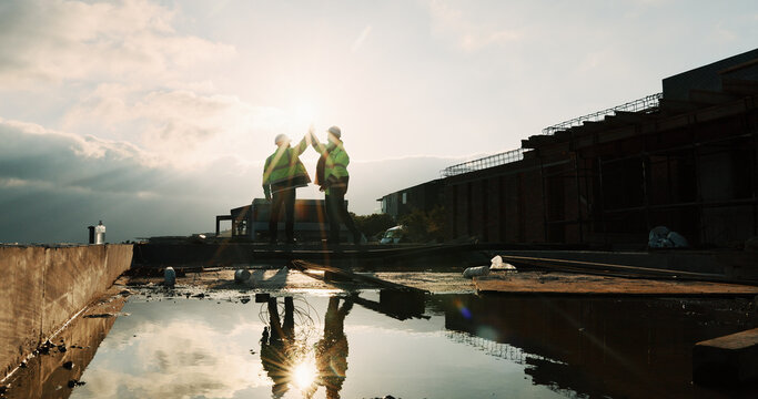 Rooftop, team or people with high five for construction, celebration or property renovation complete. Outdoor, flare or architect with support for building maintenance, project success or achievement