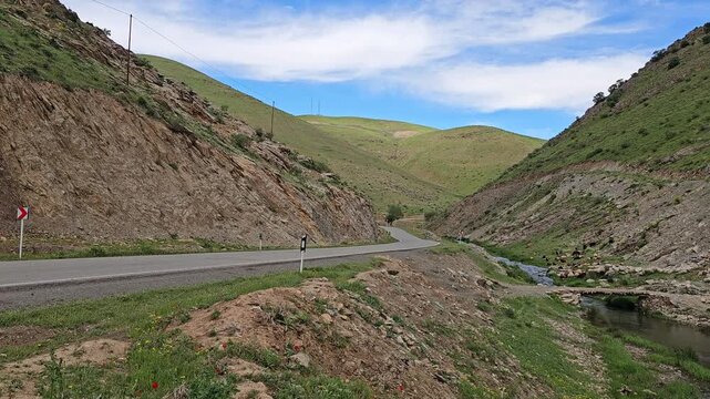 Mountain valley with a flowing stream beside a narrow road, surrounded by steep green hills, wild vegetation, and a bright sky with soft white clouds.
📍 Marivan, Kurdistan, Iran 