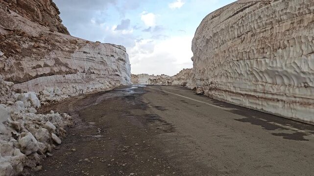 Spring roadway winding through towering snow banks in Tete heights, revealing textured melt layers and rugged mountain edges beneath shifting clouds.
📍Tatte, Hawraman Takht, Kurdistan 