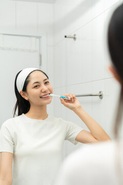 Young smiling asian woman holding brush teeth for the health of teeth in restroom. Take care and good dental health fresh breath