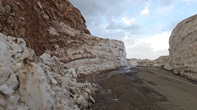 Spring roadway winding through towering snow banks in Tete heights, revealing textured melt layers and rugged mountain edges beneath shifting clouds.
📍Tatte, Hawraman Takht, Kurdistan 