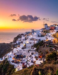 Fototapeta premium A picturesque Greek village perched on a cliffside at sunset, with white buildings, a windmill, and a vibrant sky
