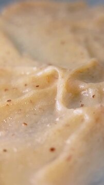 Playing with brown cream using a metal tool. Showing elastic and chewy texture. Close up view for skincare cosmetic concept.