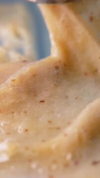 Smearing beauty cream with metal tool to display the texture and fluid consistency of the brown cream. Close up of cosmetic swatch for background.