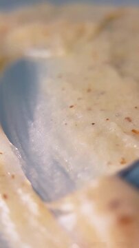 Spreading natural skin cream evenly from left to right with a metal tool applicator. Close up of cosmetic cream swatch and texture stroke.