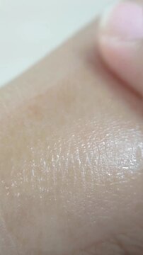 Applying milky white translucent beauty serum evenly on skin. Close up of moisturizing cosmetic routine on white background.
