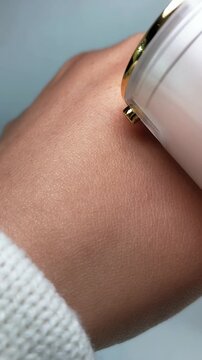 Pouring moisturizing serum onto hand skin from beauty product. Close up skincare concept for hydration and care.