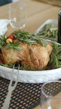 Vertical video: Pulling back cam showing roast with rosemary and fork on wood table, for serving