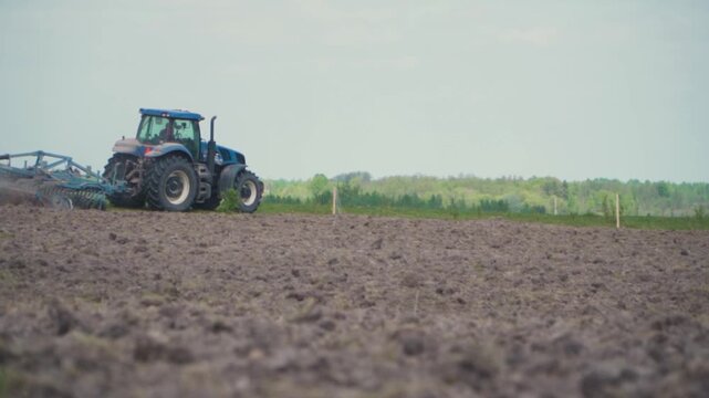 Blue Tractor Cultivating Agricultural Field on Rural Farmland